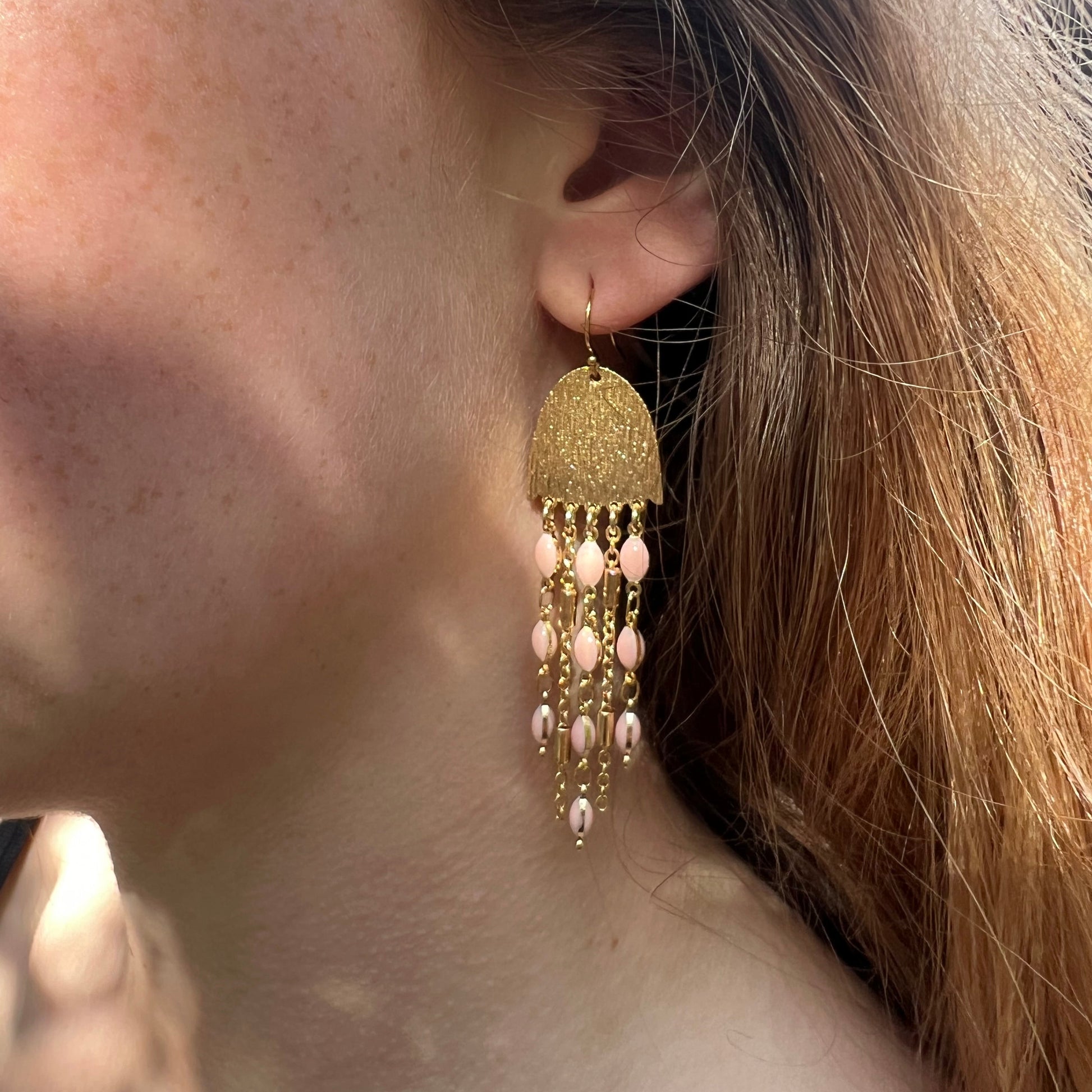 Boucles d’oreilles à chaînes rose et dorée portées 