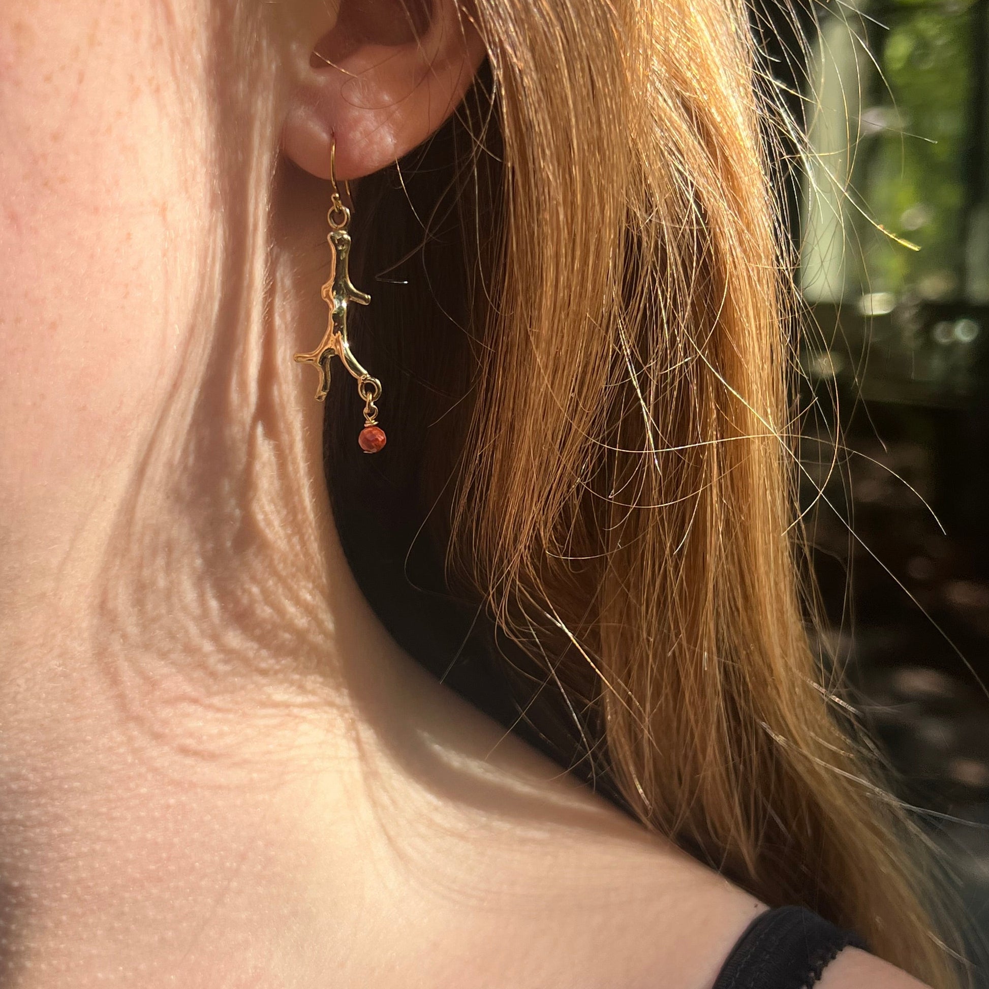 Boucles d’oreilles en branches de corail dorées avec perles rouges qui pendent 